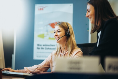 Kauffrau für Büromanagement arbeitet am PC mit Headset.