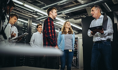 LBS Ausbilder erklärt Auszubildenden für Fachinformatik etwas im Serverraum	
