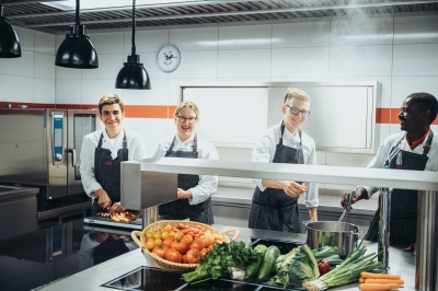 Küchenkräfte stehen in der Küche der LBS NordWest und kochen mit frischen Zutaten