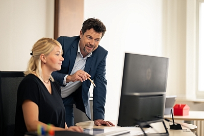 LBS-Gebietsleiter-schaut-LBS-Beraterin-vor-dem-Computer-über-die-Schulter-und-gibt-Tipps LBS-Gebietsleiter schaut LBS-Beraterin vor dem Computer über die Schulter und gibt Tipps.