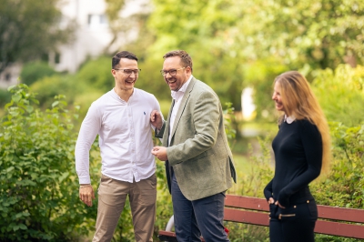 Drei-LBS-Baufinanzierungsberater-und-Beraterinnen-lachen-gemeinsam-draußen-im-Grünen