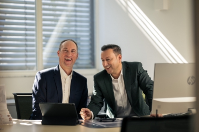 Zwei LBS-Berater sitzen lachend nebeneinander im Büro.